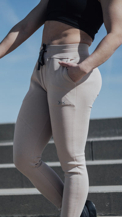 Torso inferior de una mujer con unos pantalones jogger de color beige